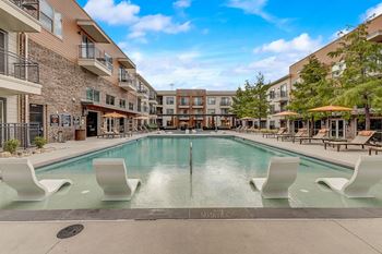 A swimming pool surrounded by white chairs and buildings.